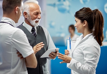 Doctors review tablet together in hospital hallway at US Heart and vascular