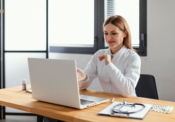 Doctor using laptop at desk in bright office at US Heart and vascular