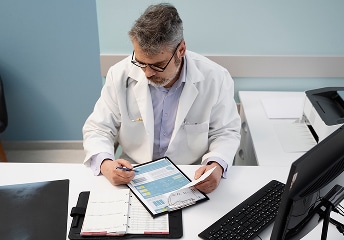 Cardiovascular Physician writes notes while using a tablet at US Heart and vascular