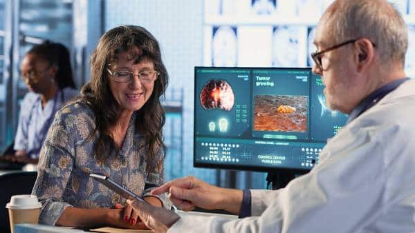 Doctor consults patient beside diagnostic monitors at US Heart and vascular